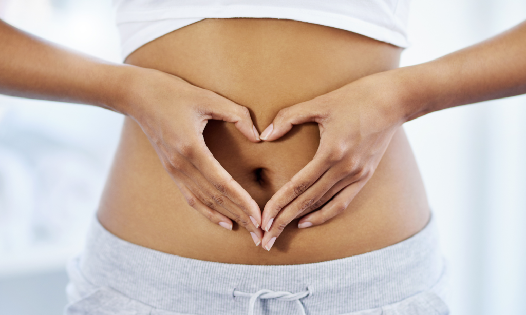 Benessere intestinale: una donna ha le mani a forma di cuore davanti all'ombelico